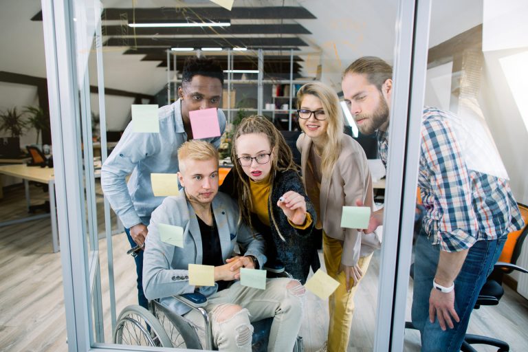 Inclusion for disabled people. Group of young multiracial business people with one handicapped man