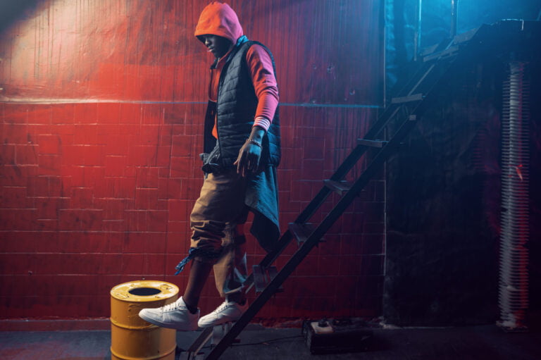 Stylish rapper in hoodie posing in grunge studio, rave hoodie styling inspiration.