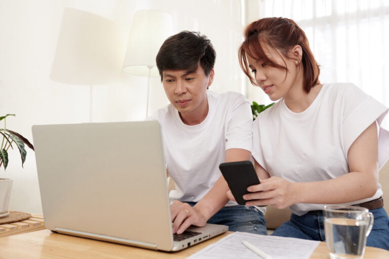 Couple filling out online form and reviewing information on smartphone