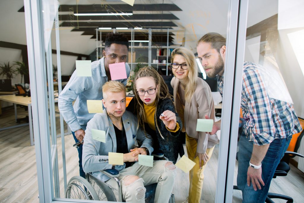 Inclusion for disabled people. Group of young multiracial business people with one handicapped man
